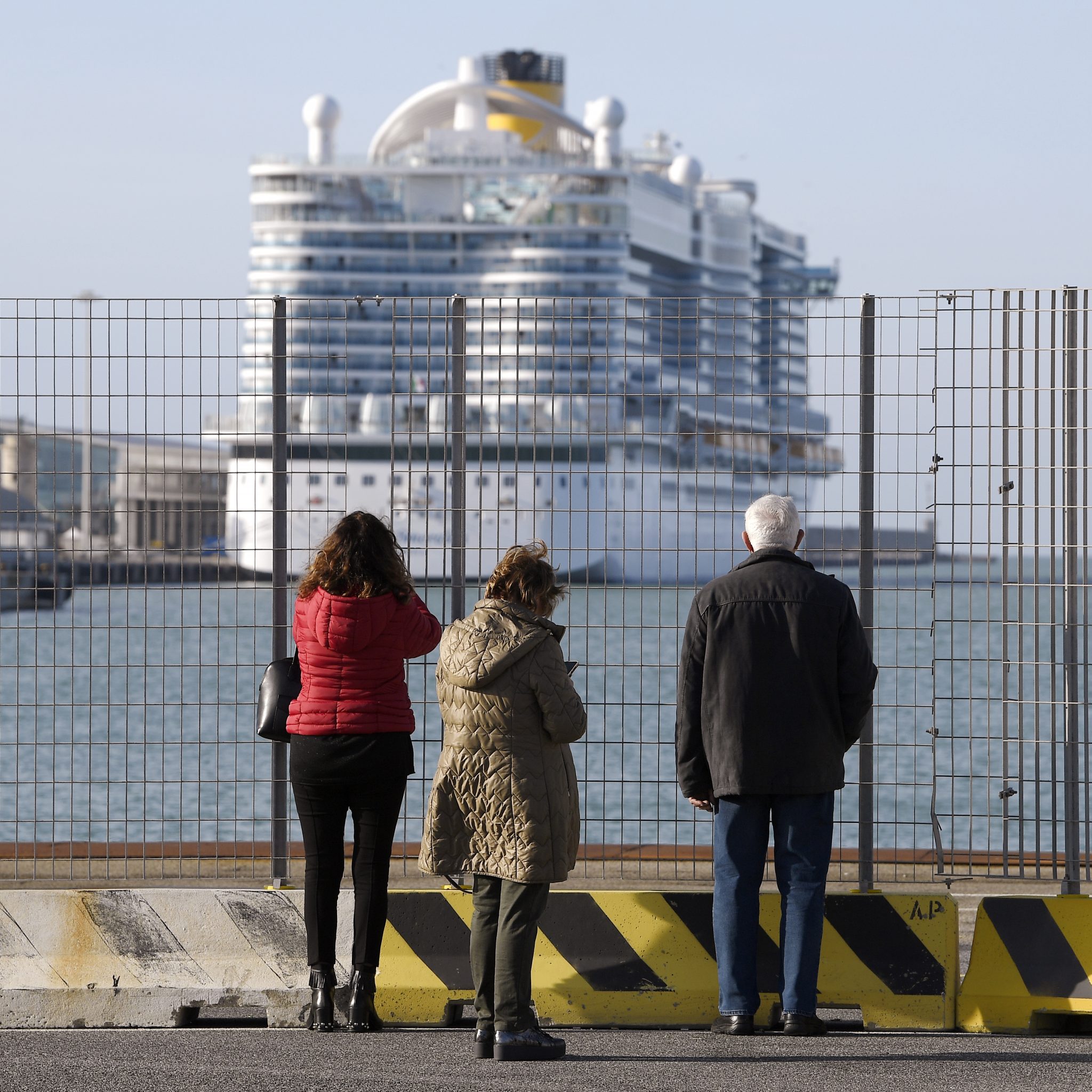 Mensen kijken naar de Costa Smeralda in de haven van Cvitavecchia. Meer dan 6000 gasten mochten het schip niet verlaten, nadat bij twee Chinese passagiers ziek waren gemeld. Ze bleken echter niet besmet met het coronavirus. (Foto Filippo Monteforte / AFP)