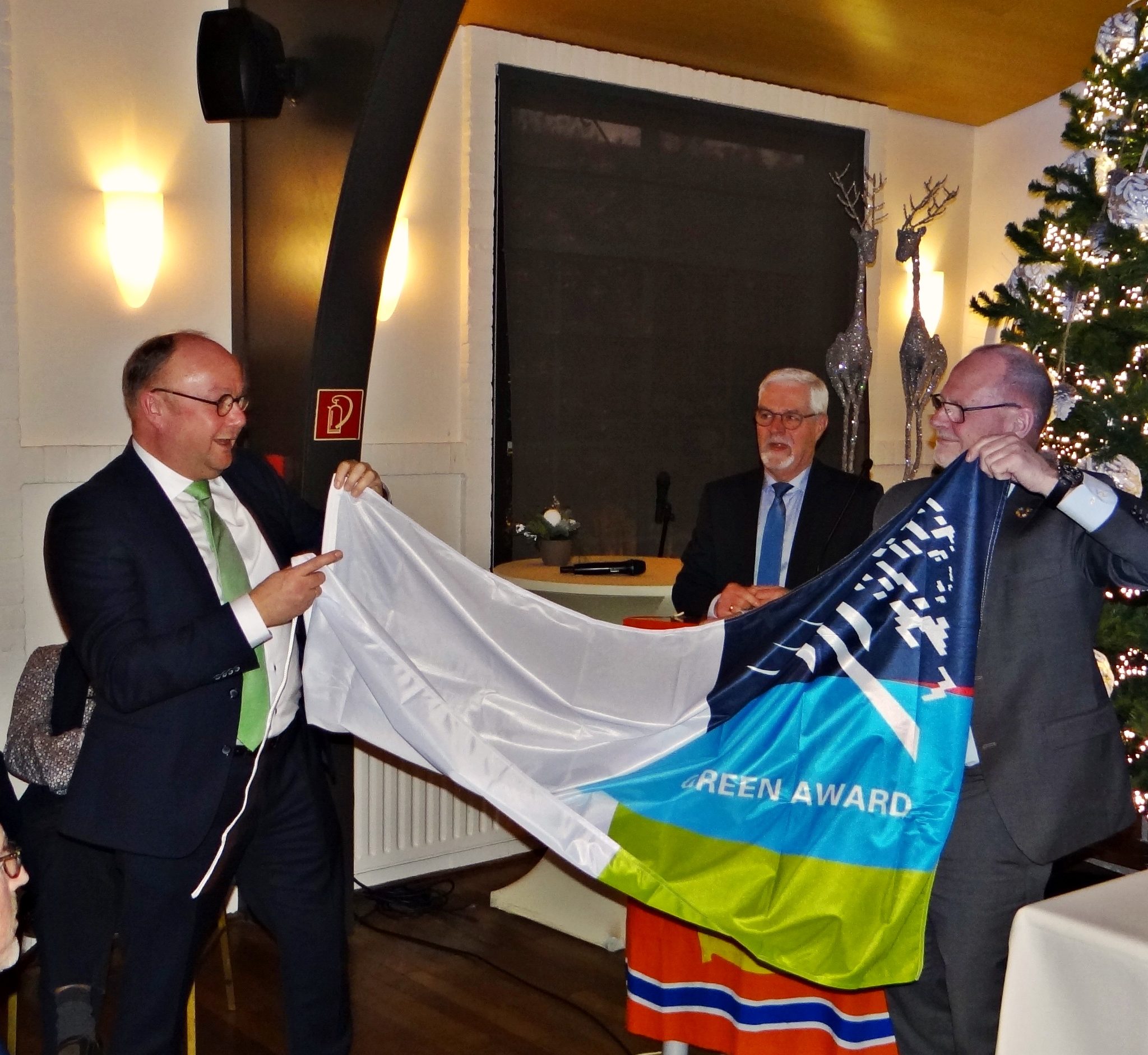 Wethouder Ton Spek (gemeente Sliedrecht) ontvangt een vlag van de Green Award Foundation uit handen van directeur Jan Fransen (rechts). Op de achtergrond afdelingsvoorzitter Joop van Belle. (Foto Dick den Braber)