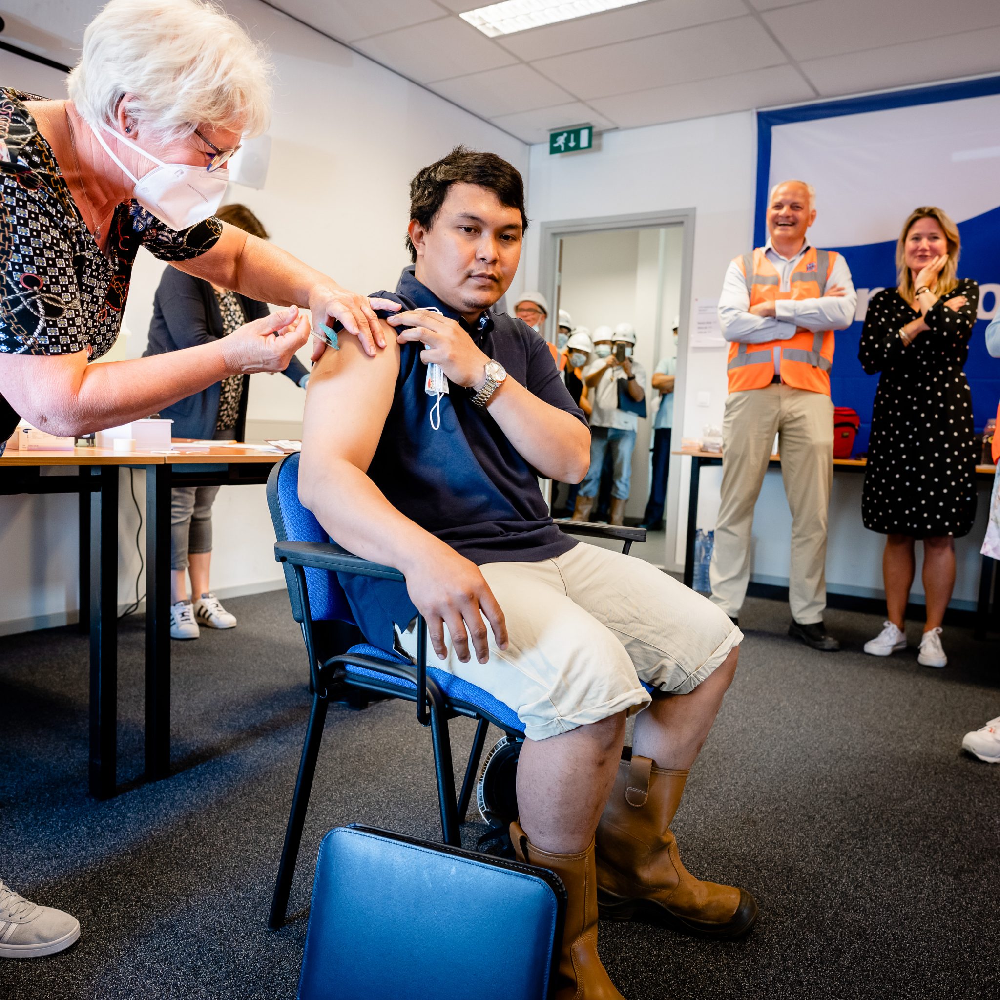 Tijdens de vaccinatiecampagne wordt een zeevarenden geprikt onder toeziend oog van Annet Koster KVNR (2e van rechts) en toenmalig minister van Infrastructuur en Waterstaat Cora van Nieuwenhuizen (rechts). (Foto KVNR)