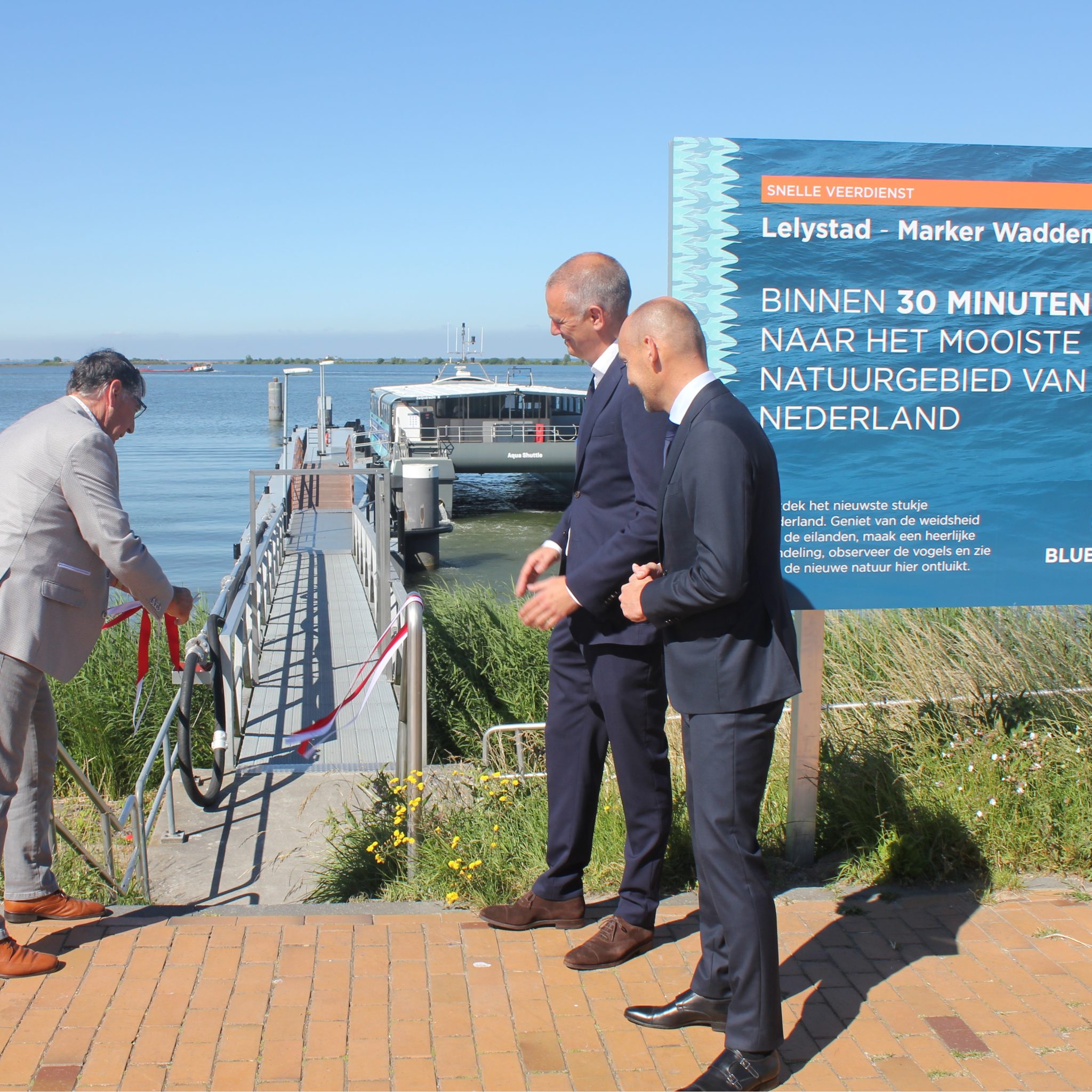 Wethouder Luc Baaten van Lelystad opent de veerdienst aan de nieuwe steiger in de Bataviahaven. Op de achtergrond de catamaran waarmeer Blue Amigo de dienst onderhoudt. (Foto Blue Amigo)