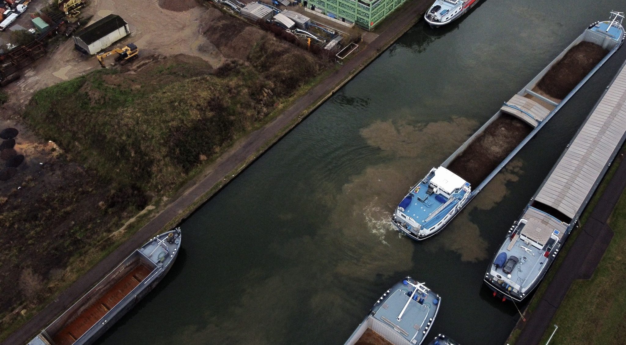 Luchtopname vanuit een drone toont schepen die op een rij liggen voor een gesloten sluis in het Albertkanaal in Wijnegem.